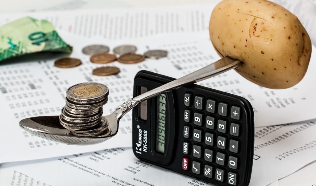 calculator balancing spoon with coins and potato